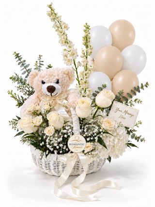 Small white basket with ivory flowers, a cream teddy bear, balloons and a greeting card.